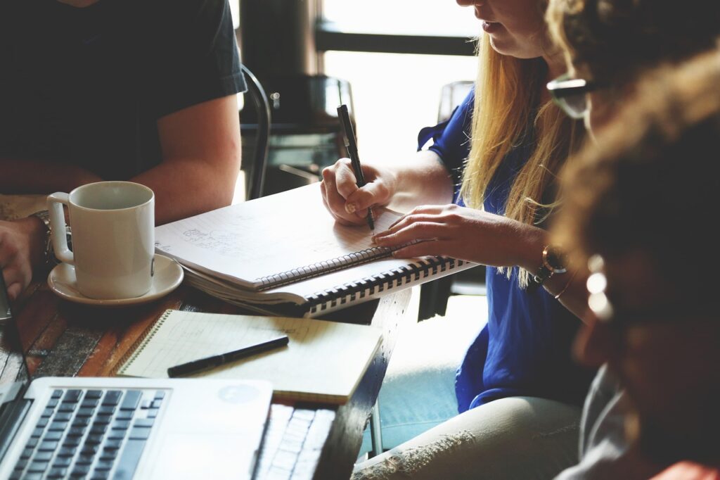 Was ist New Work: Eine Definition findest du in diesem Blogartikel. Die Prinzipien von Selbstorganisation, Ganzheit und evolutionärem Sinn bieten Orientierung, um eine zukunftsweisende Arbeitskultur zu etablieren. Auf dem Foto ist ein Team zu sehen, wie es zusammenarbeitet.