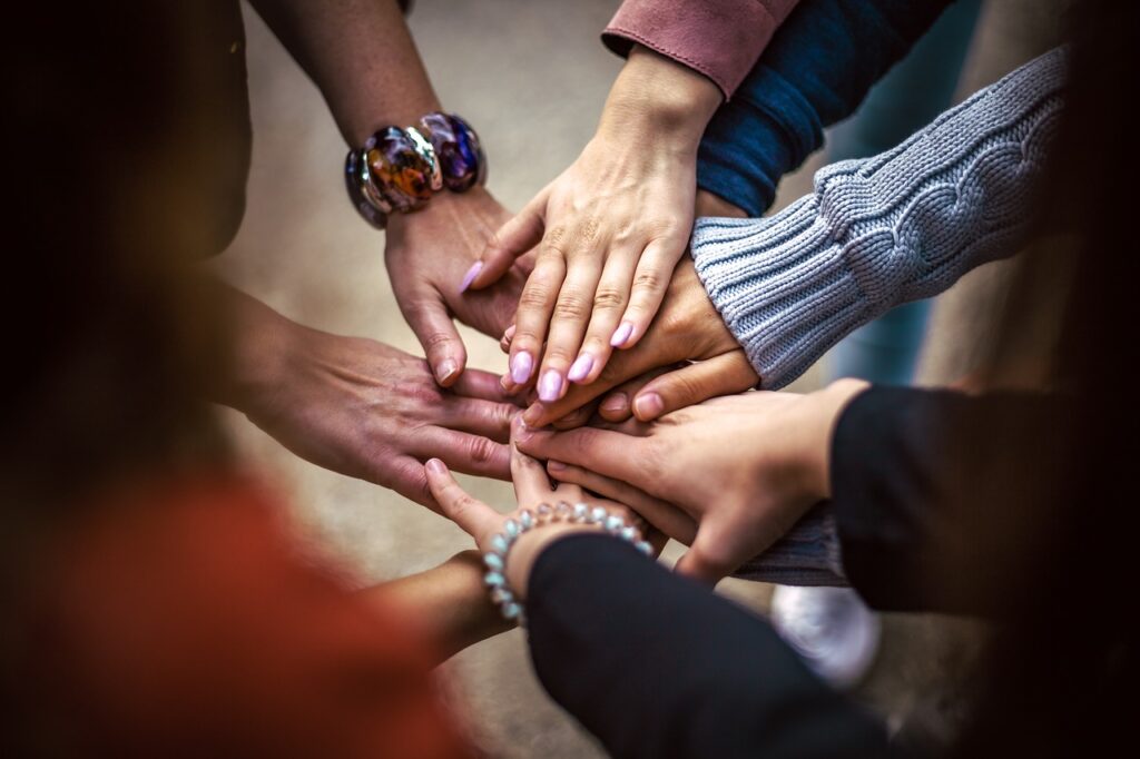 Team stärken: Spürst du, dass der Stress im Team immer mehr zunimmt? Wünschst du dir wieder eine ausgeglichene Atmosphäre? In diesem Blogartikel bekommst du 4 Schlüssel für krisenfeste Teams. Auf dem Foto sind die Hände eines Teams zuu sehen.